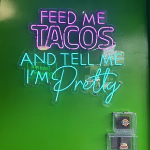 a neon sign that reads feed me tacoss and tell me i&apos;m pretty