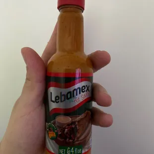 a hand holding a bottle of hot sauce