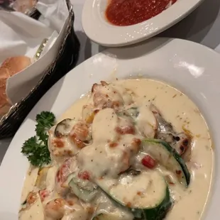 Chicken louisiana is served with some angle hair pasta and sauce.