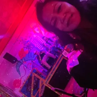 a woman standing in front of a pink lit room