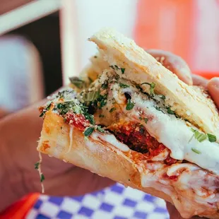 a hand holding a piece of pizza