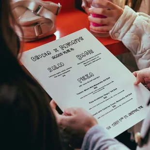a woman holding up a menu