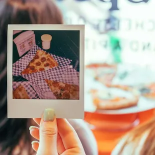a woman holding up a polaroid picture