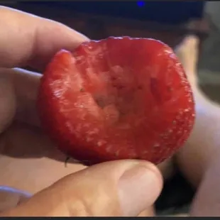 a hand holding a strawberry