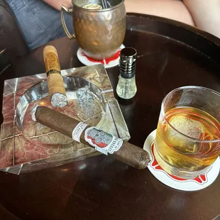 a glass of whiskey and a cigar on a table