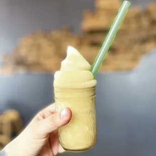 a hand holding a mason jar with a smoothie in it