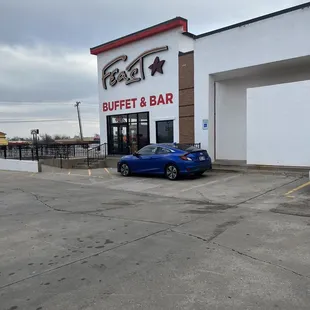 a blue car parked in front of a restaurant