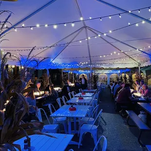 tables and chairs under a tent with string lights