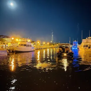 a full moon over a harbor at night