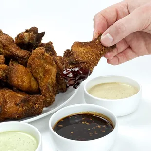 a plate of fried wings and dipping sauces