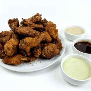 a plate of fried wings and dipping sauces