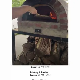a person putting a pizza into a brick oven