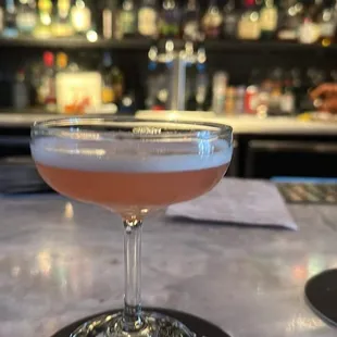 a pink cocktail in a coupe glass