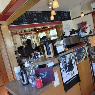 a coffee shop counter with a menu on the wall