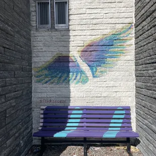 a painted bench in front of a brick wall