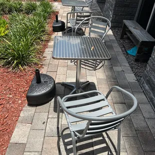 Two metal tables with no cover from the sun. The air conditioning units above them drip water on top of you.