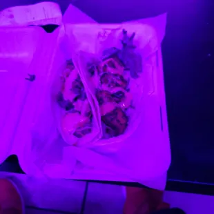 a person holding a plate of food in front of a purple light