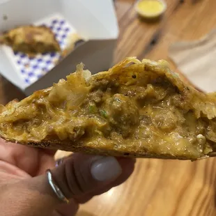 a hand holding a piece of pizza