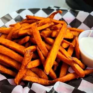 a basket of sweet potato fries with a dipping sauce
