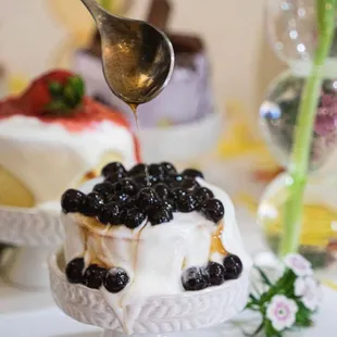 a spoon drizzling blueberries onto a dessert