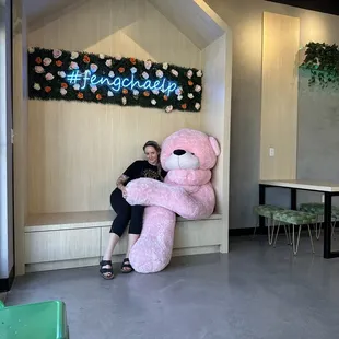 a woman sitting with a large pink teddy bear