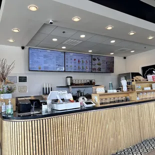 a restaurant counter with a menu on the wall