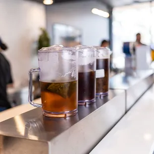 a row of mugs of tea on a counter