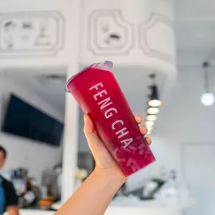 a person holding a red drink