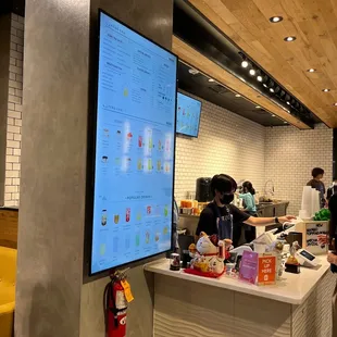 a restaurant counter with a menu displayed on the wall