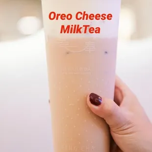 a person holding a cup of oreo cheese milk tea