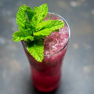 a glass of a drink with a sprig of mint