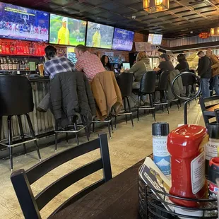 people sitting at the bar watching tvs