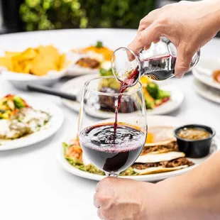 a person pouring red wine into a glass