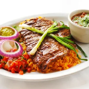 Carne Asada - Marinated, grilled beef served on a bed of rice along w/ fresh guacamole,
 sour cream, pico de gallo, a cup of Mex bean soup