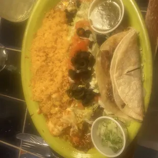 Beef enchilada garnished with complementary tomatoes and olives, El Pastor taco with cilantro and onion, side of rice