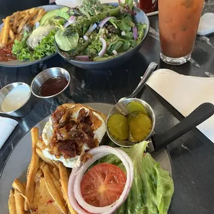 Over view of two burgers, fries, salad and Tito's Bloody Mary