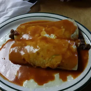 two burritos on a plate with sauce