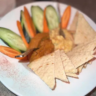 a plate of pita chips, carrots, cucumbers, and cucumber