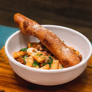 a bowl of pasta and breadsticks