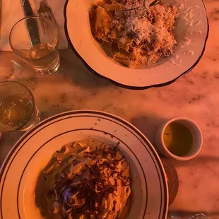 two plates of pasta on a marble table