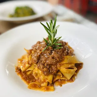 a plate of pasta with a sprig of rosemary