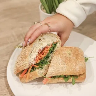 a person holding a sandwich on a plate