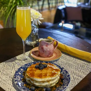 a plate of pancakes and a glass of orange juice