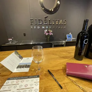 a glass of wine and menus on a wooden table