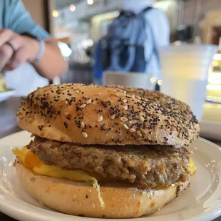 a hamburger on a plate with a man in the background