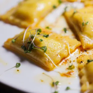 a plate of ravioli with cheese and herbs
