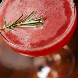 a closeup of a cocktail with a sprig of rosemary