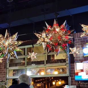 people sitting at a bar with christmas decorations hanging from the ceiling