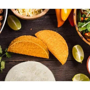 a variety of mexican food including tortillas, salsa, limes, and other toppings