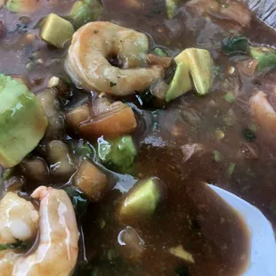 a bowl of soup with shrimp and avocado